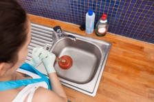 woman using plunger in drain 