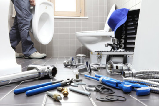 Plumber installing new toilet with tools on floor